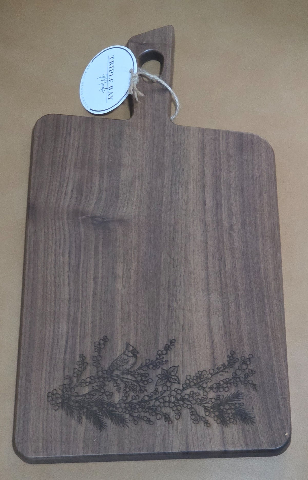 Front of walnut-finished acacia serving board engraved with a cardinal, berries and evergreen branches
