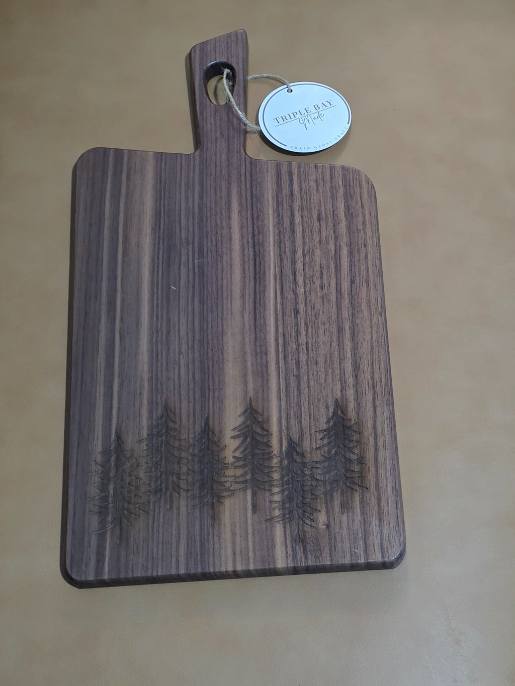 Acacia serving board with walnut finish and evergreen forest engraving along the lower edge