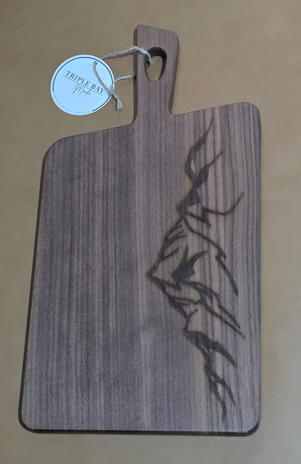 Walnut-finished acacia serving board with angular mountain ridge engraving along the right edge