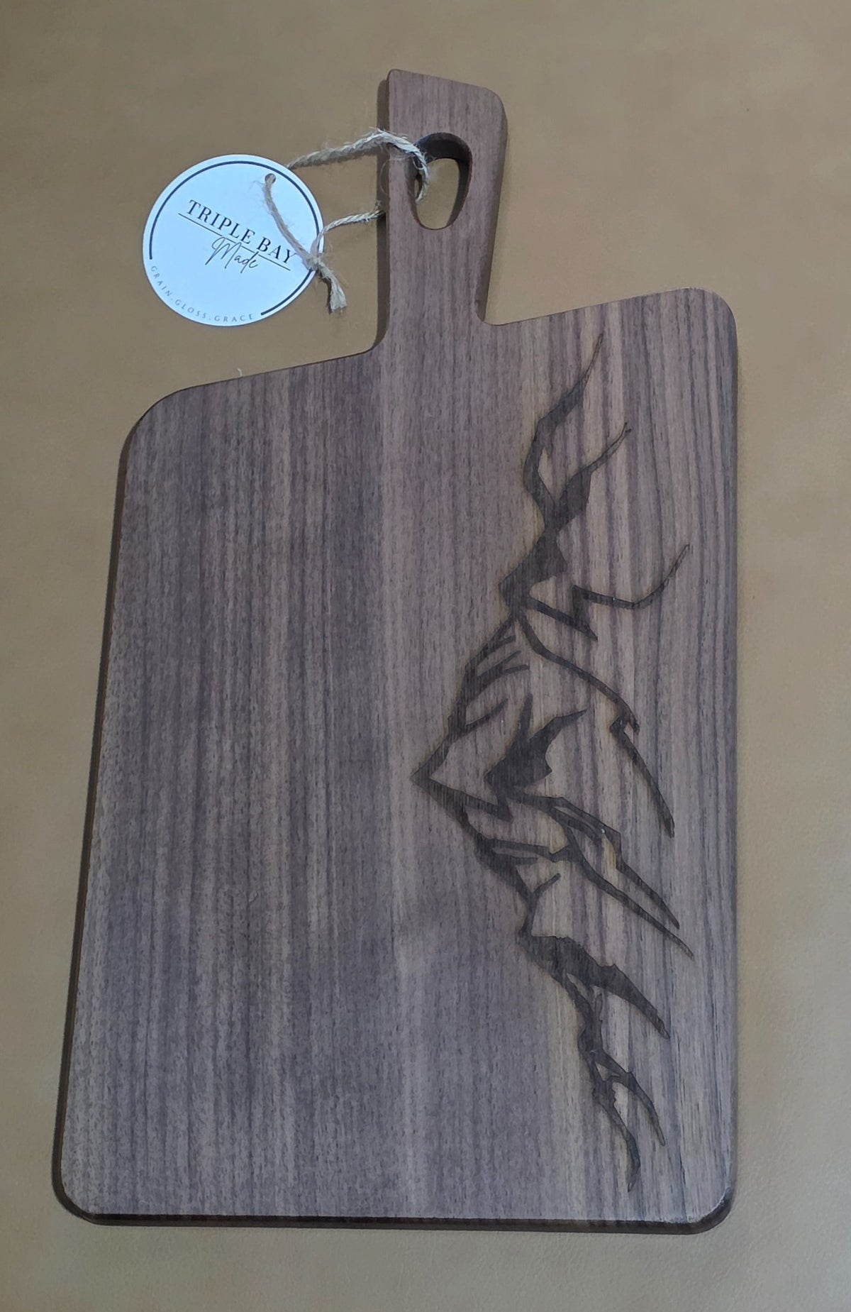 Walnut-finished acacia serving board with angular mountain ridge engraving along the right edge