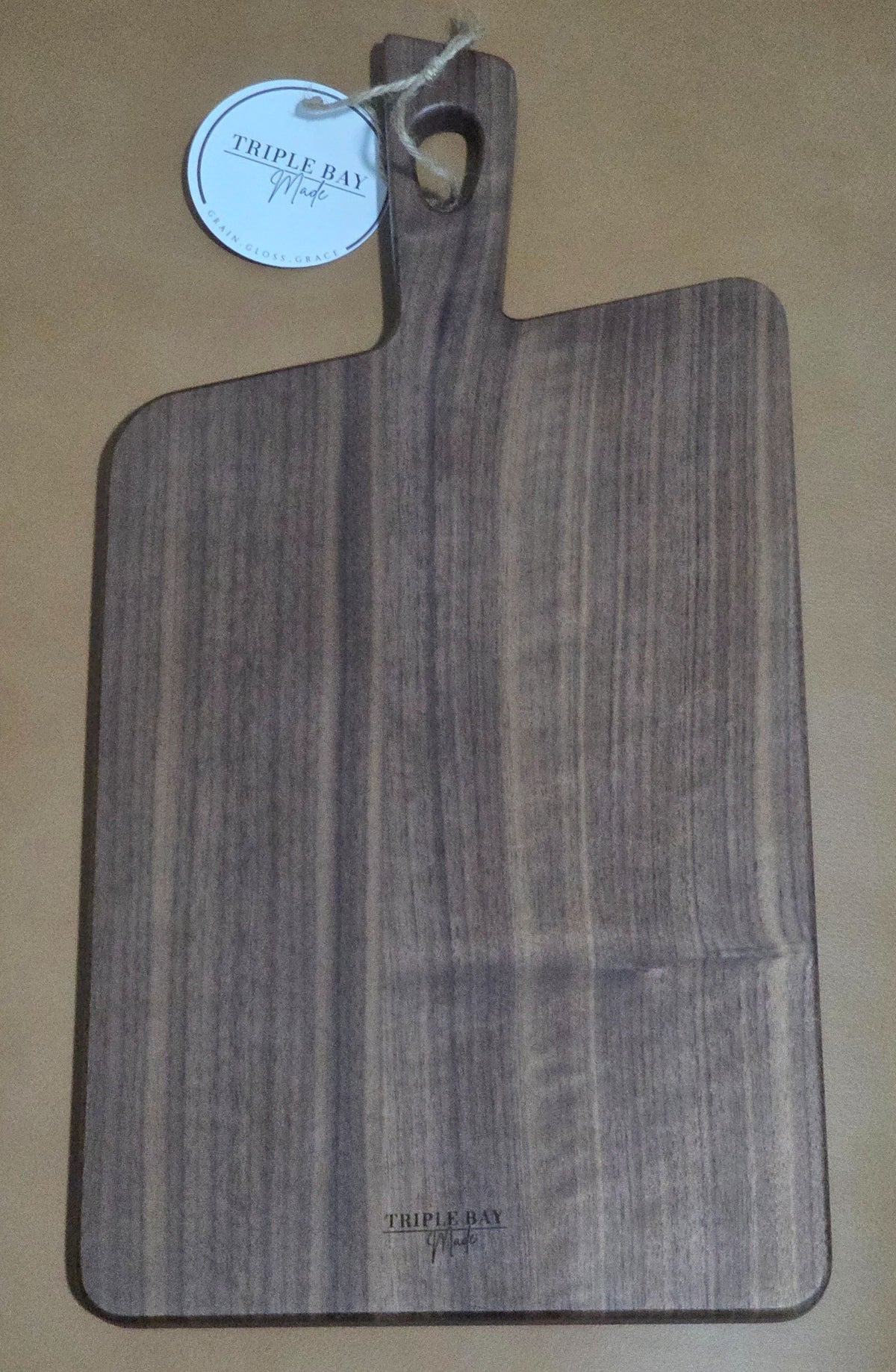 Reverse of acacia paddle serving board with Triple Bay Made maker mark