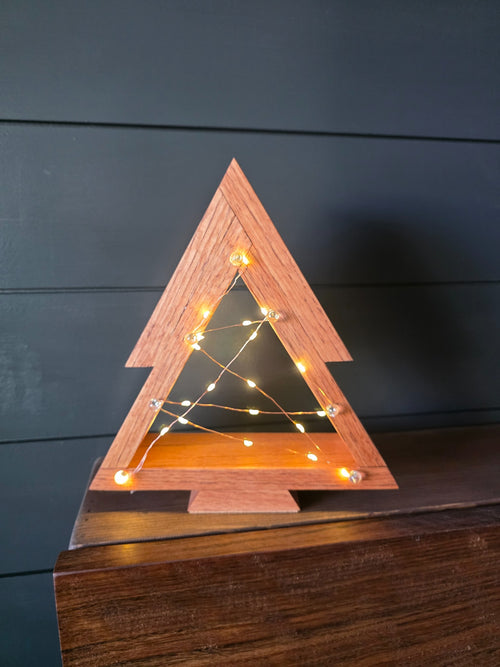 Front view of premium white oak Christmas tree with chestnut stain and fairy lights across its open center
