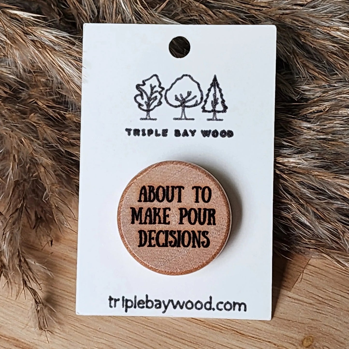 Laser-engraved wooden pin with 'about to make pour decisions' text on backing card