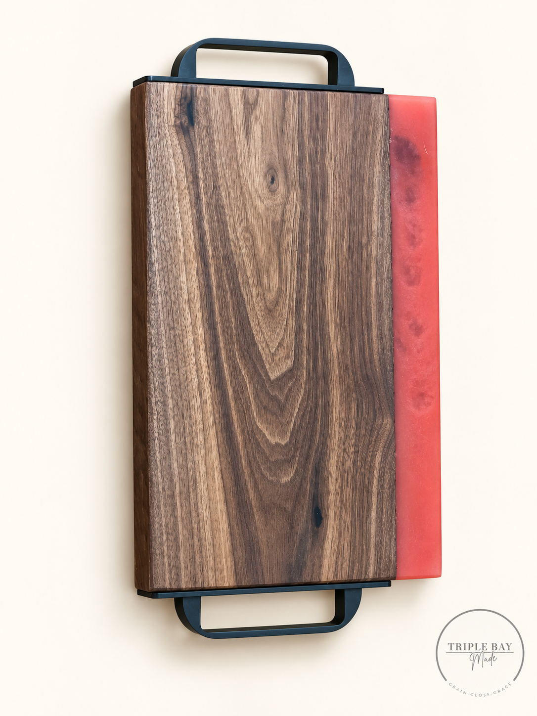 Front of premium walnut serving tray with coral-red resin edge and black loop handles