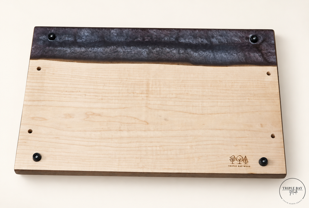 Underside of ambrosia maple resin tray showing four black feet, handle mounting holes and Triple Bay Wood mark