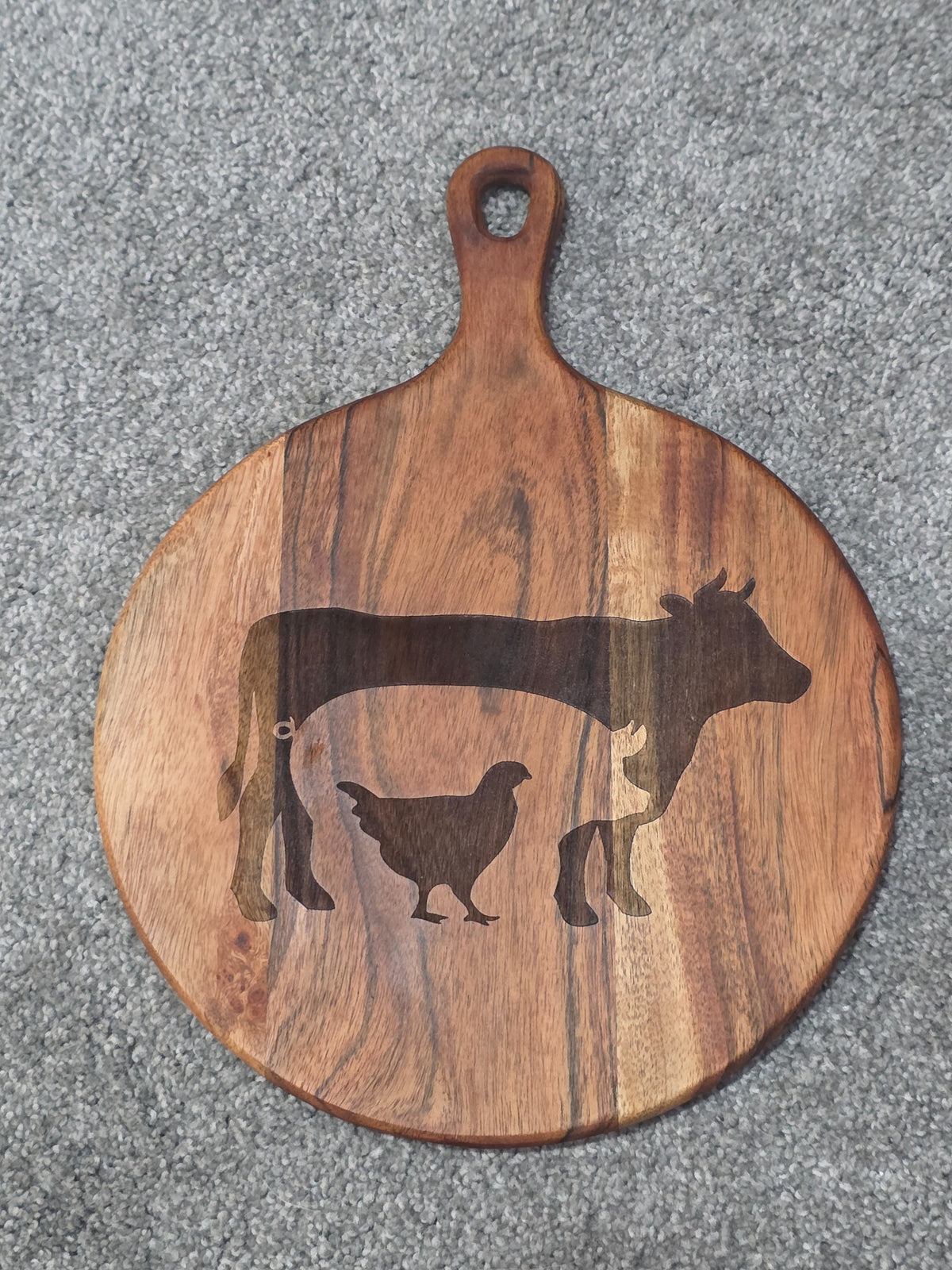 Reverse of round acacia board showing warm grain bands, oval hanging hole and Triple Bay Made maker mark