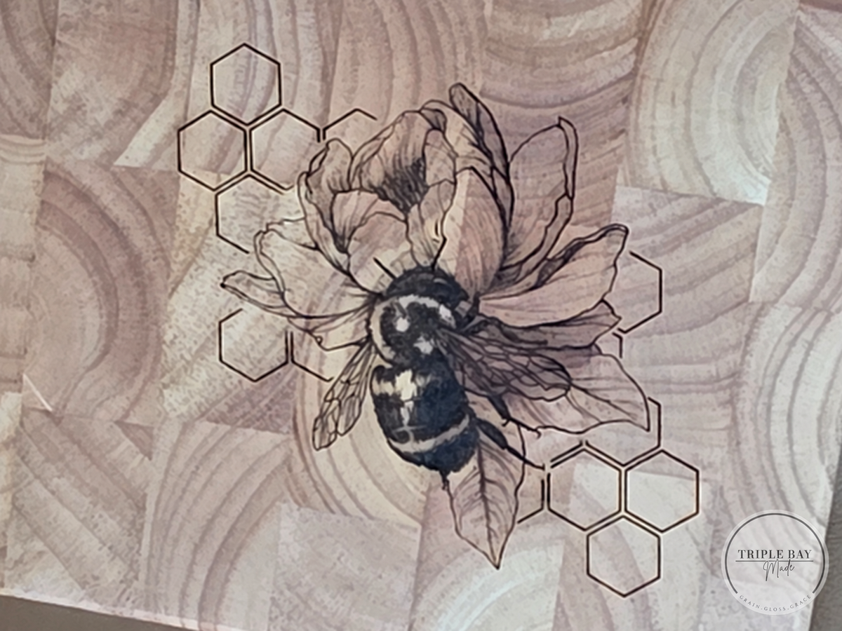 Close-up of the bee, flower petals and honeycomb engraving across the natural end-grain wood