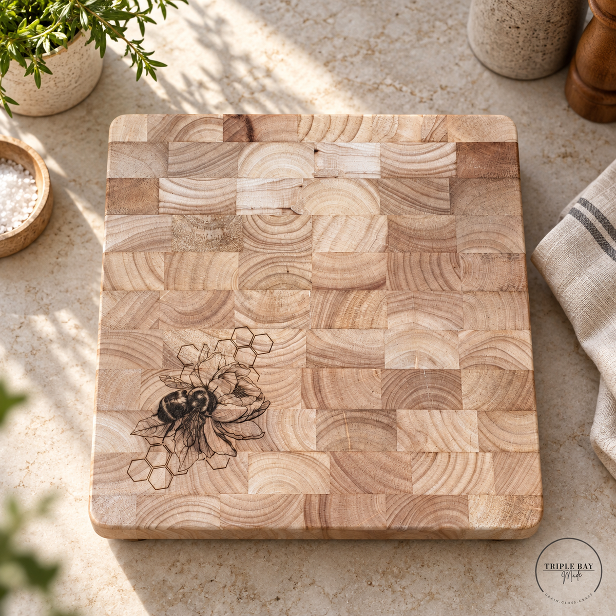 Honey and Hive bee-engraved end-grain cutting board on a light stone kitchen counter with neutral decor