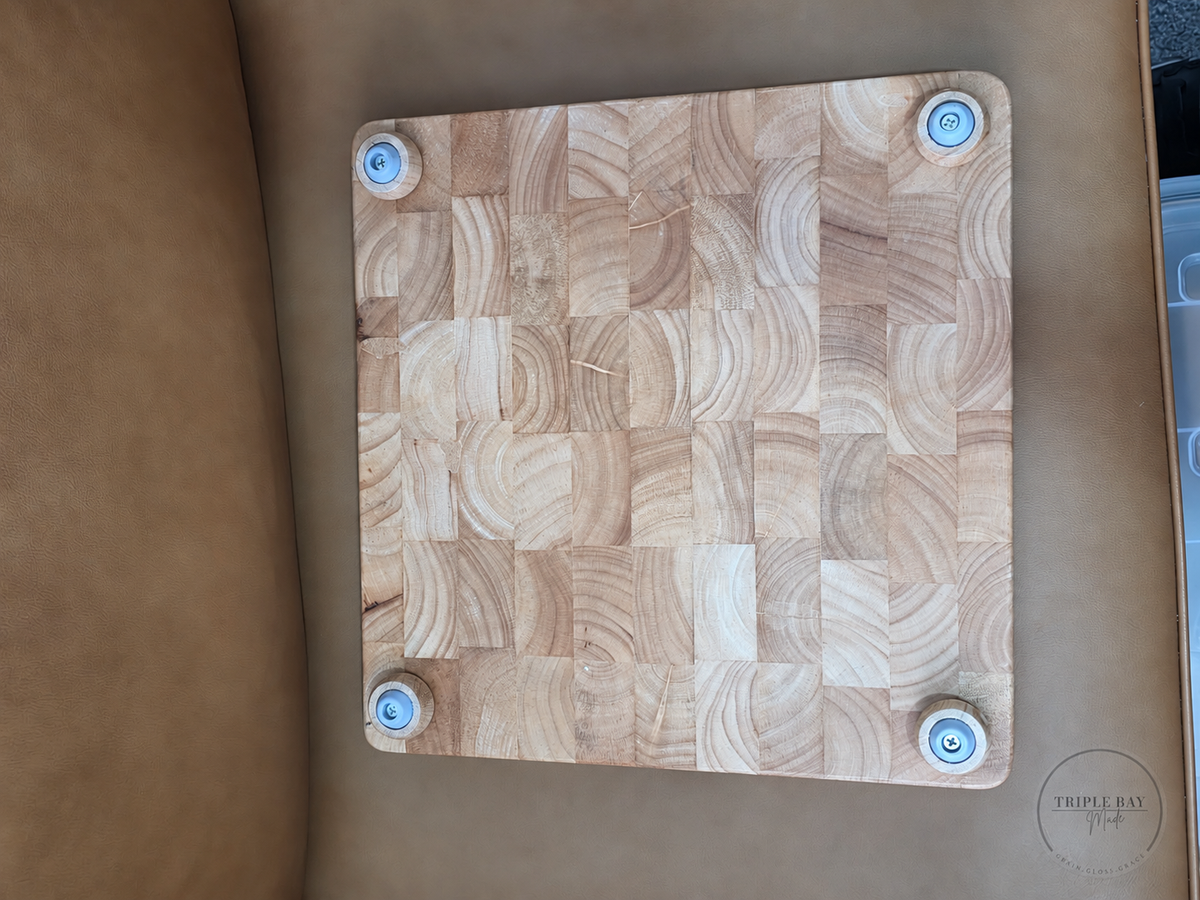 Underside of the end-grain wood cutting board showing four screw-mounted feet