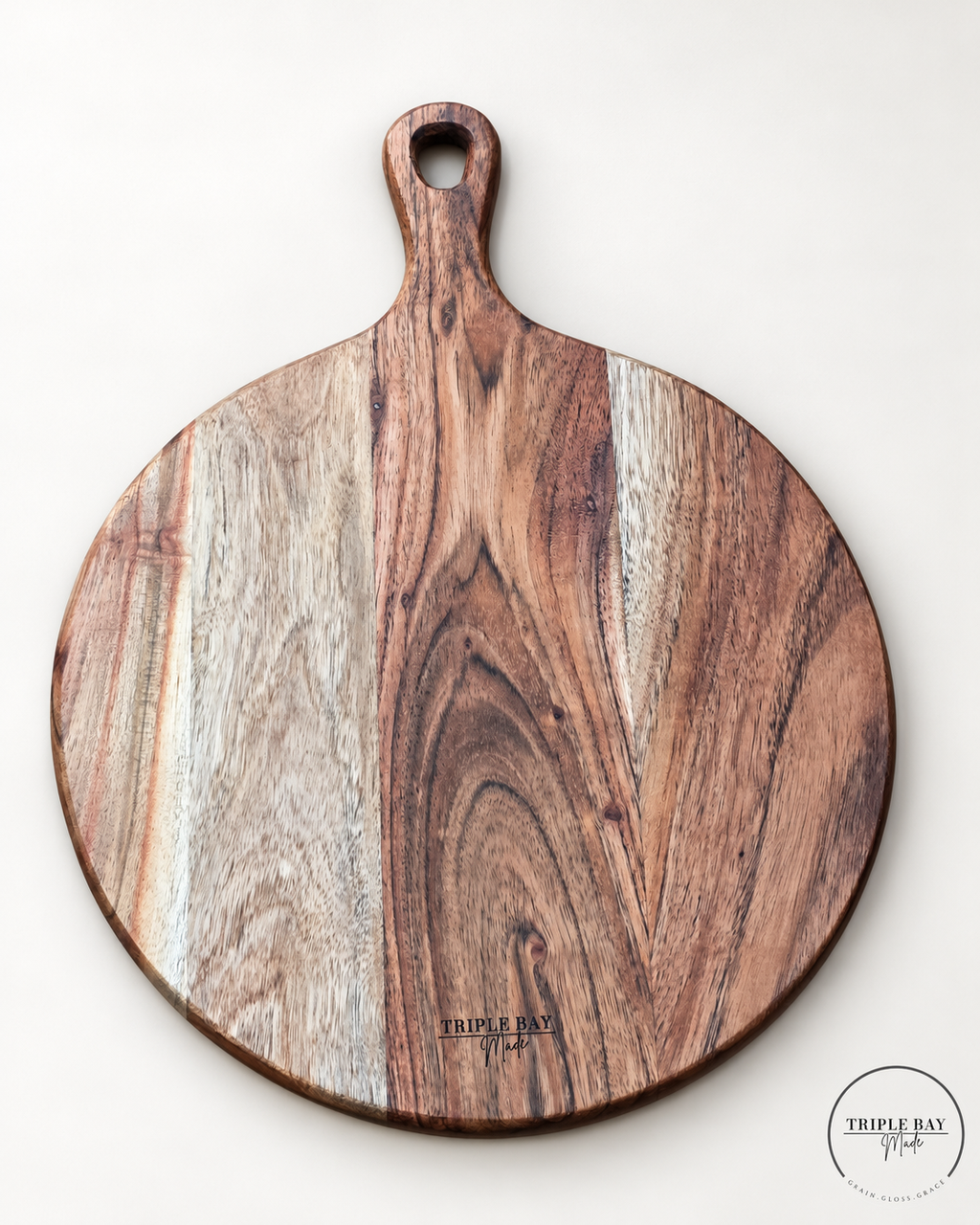 Reverse of round acacia paddle board showing pale grain bands, natural knots and Triple Bay Made maker mark