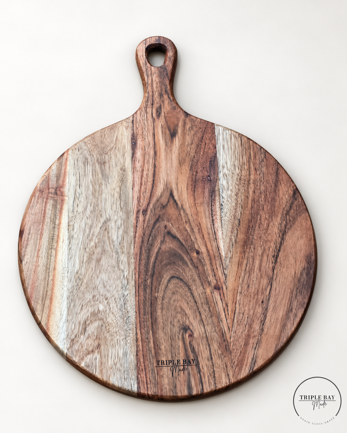 Reverse of round acacia paddle board showing pale grain bands, natural knots and Triple Bay Made maker mark