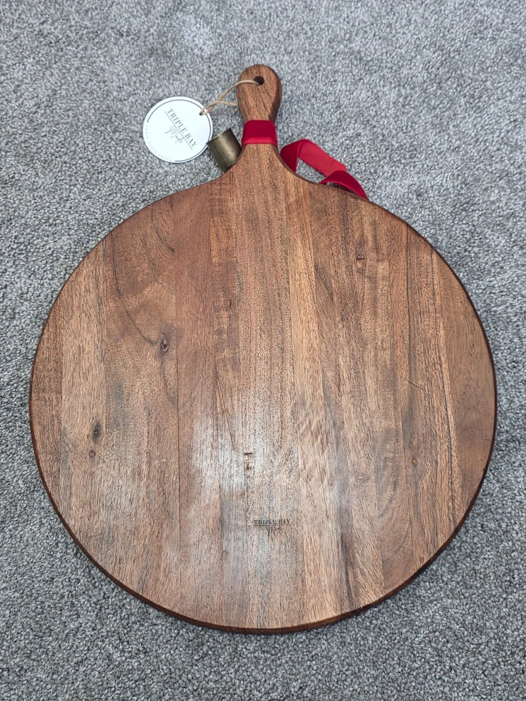 Reverse of large round acacia serving board showing wood grain and paddle handle