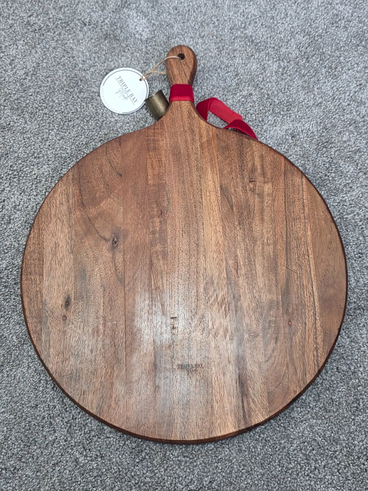 Reverse of large round acacia serving board showing wood grain and paddle handle