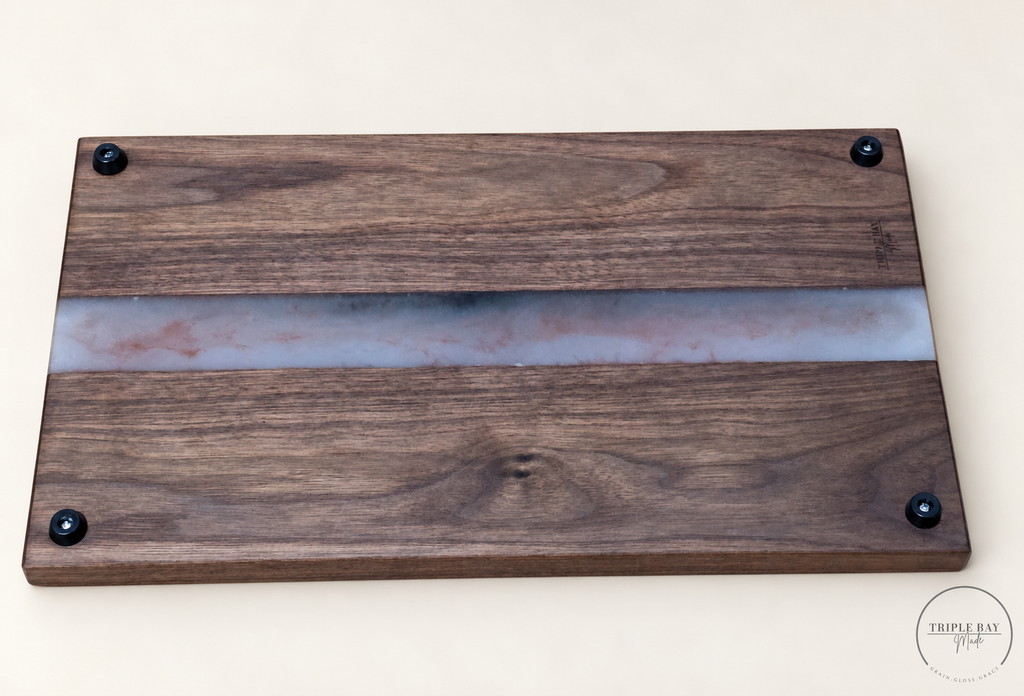 Underside of walnut and resin board showing four black feet and Triple Bay Made maker mark