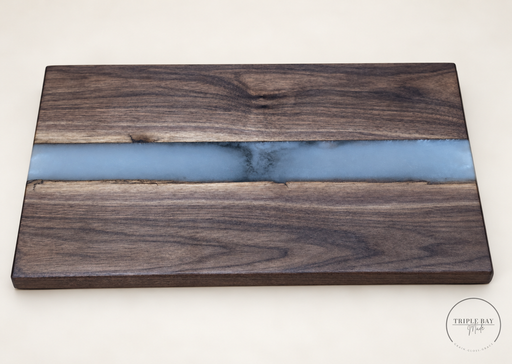 Premium walnut serving board with a pale blue-gray resin river and smoky center, angled front view