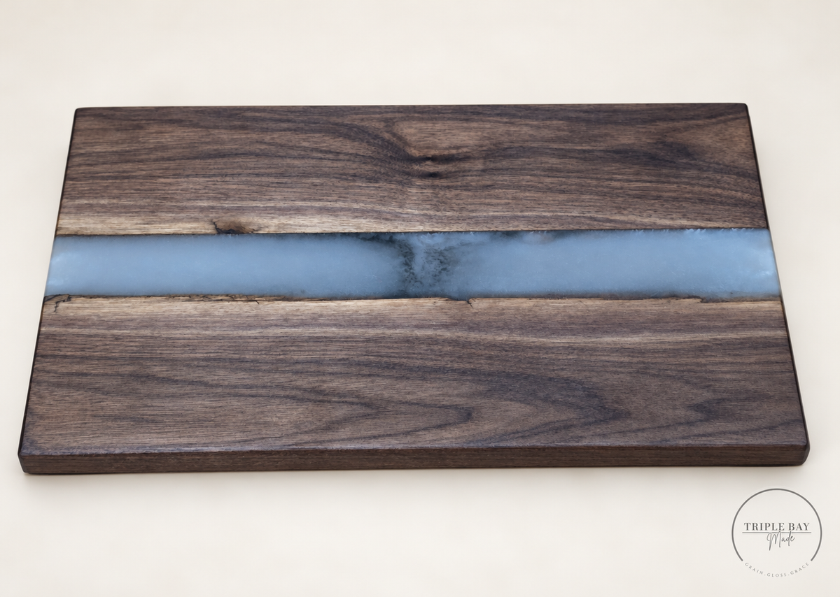 Premium walnut serving board with a pale blue-gray resin river and smoky center, angled front view