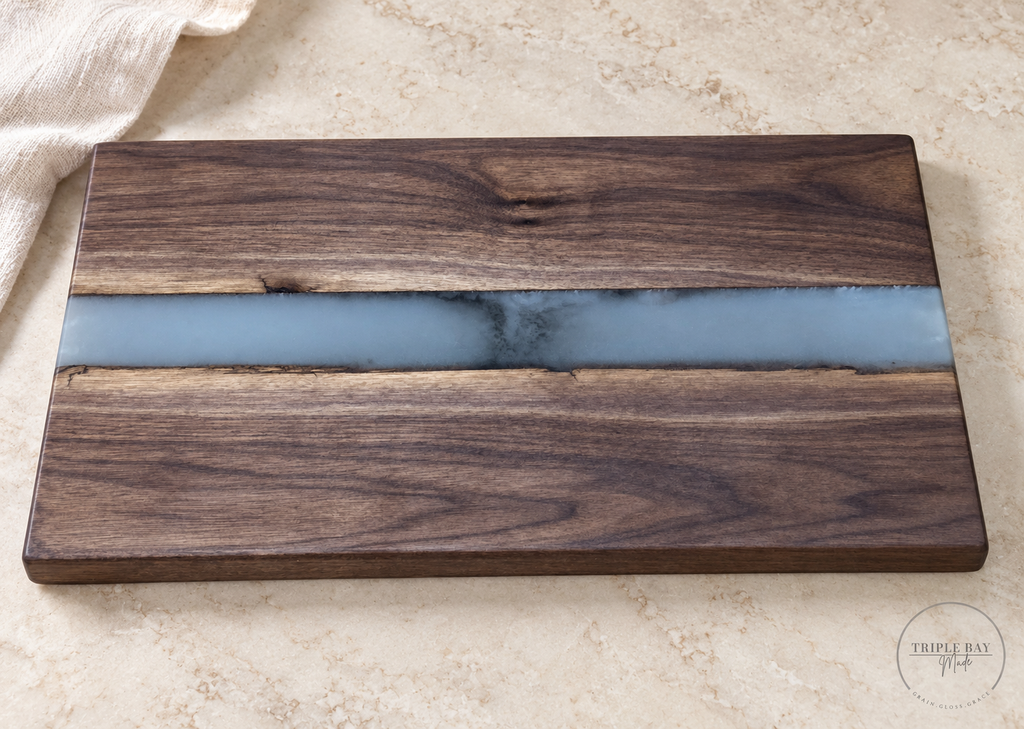 Walnut and blue-gray resin river serving board styled on light stone beside ivory linen