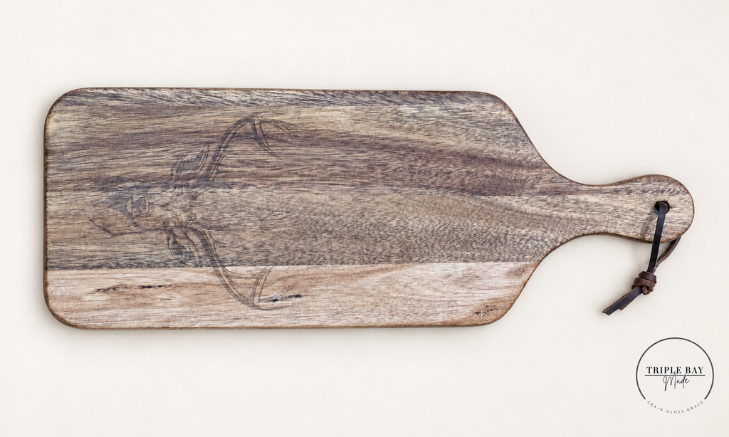 Front of long acacia paddle board with subtle longhorn skull engraving, pale wood band and hanging cord