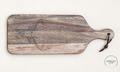 Front of long acacia paddle board with subtle longhorn skull engraving, pale wood band and hanging cord