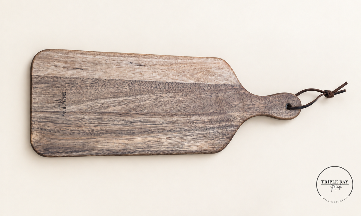 Reverse of acacia paddle board showing varied wood grain, Triple Bay Made maker mark and handle cord