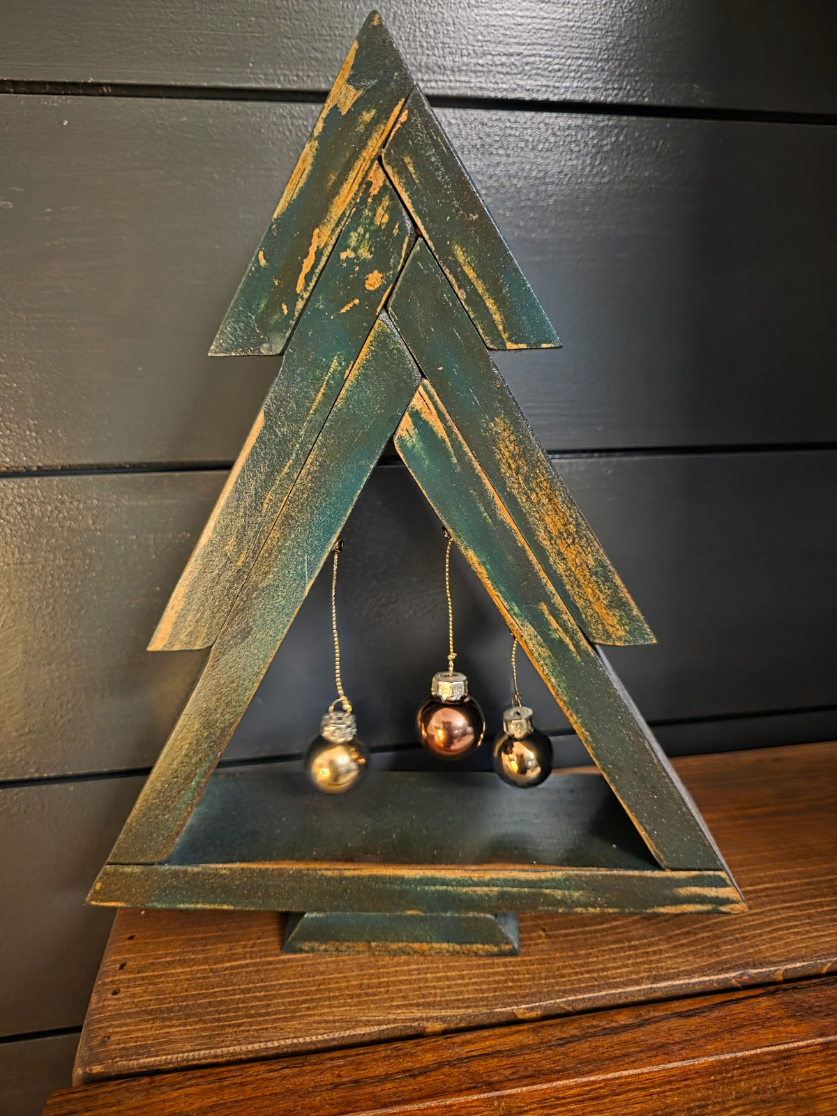 Distressed green stained pine Christmas tree with three hanging ornaments