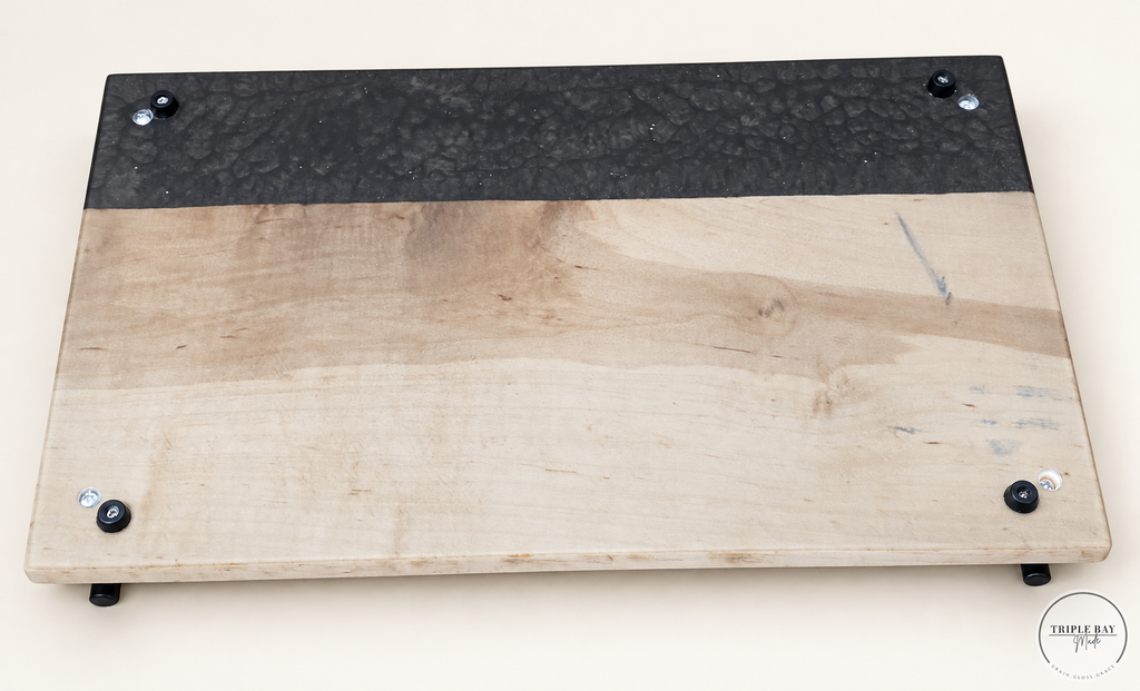 Underside of maple and charcoal resin tray showing four black feet and handle fasteners