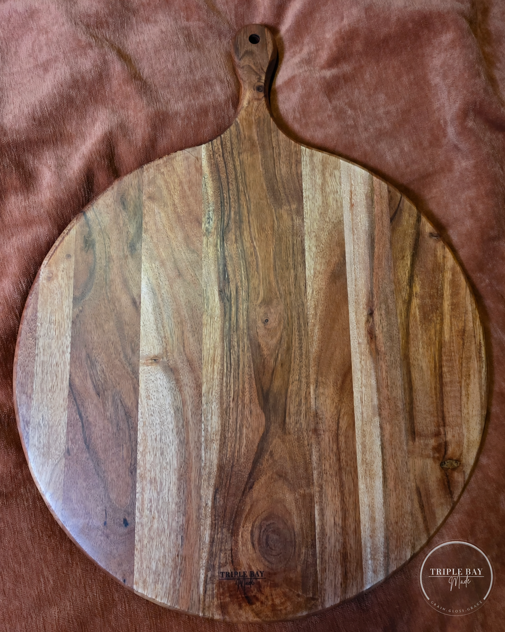 Plain reverse of the round acacia paddle board with natural wood grain and Triple Bay maker's mark